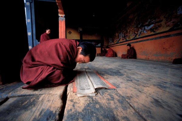 A young monk learning his prayers at the entrance to a chapel in Bhumthang (Bhutan)