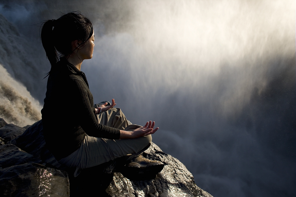 Varunee, adepte de yoga et de méditation, au sommet des chutes de Dettifoss en Islande