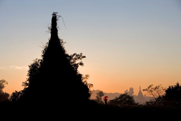 In Sittwe, to the West of Myanmar, two young women take a walk near a stupa covered by jungle vegetation.